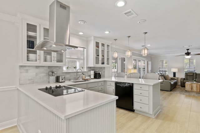 kitchen featuring island range hood, kitchen peninsula, hanging light fixtures, black appliances, and sink