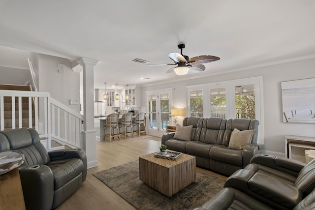 living room featuring ceiling fan, decorative columns, ornamental molding, and light hardwood / wood-style flooring