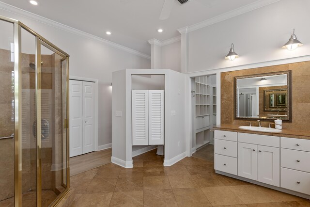 bathroom with a shower with shower door, vanity, ceiling fan, and crown molding