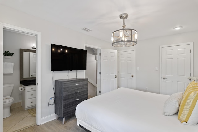 bedroom with ensuite bathroom and an inviting chandelier