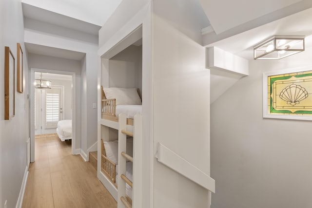 corridor with an inviting chandelier and light hardwood / wood-style floors