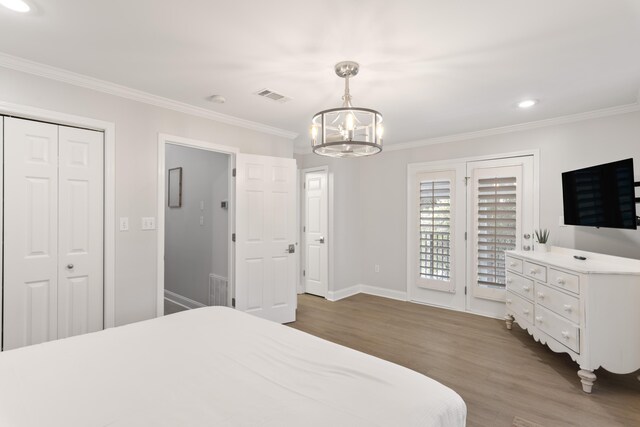 bedroom with a notable chandelier, dark wood-type flooring, access to exterior, a closet, and crown molding