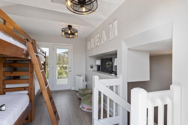 staircase featuring hardwood / wood-style flooring, a notable chandelier, and vaulted ceiling