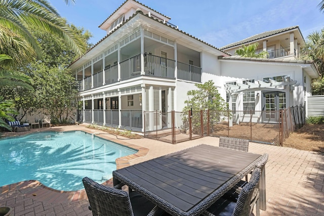 back of house with a balcony, a fenced in pool, and a patio