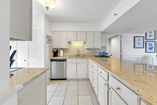 kitchen with sink, tasteful backsplash, stainless steel dishwasher, light stone countertops, and white cabinetry