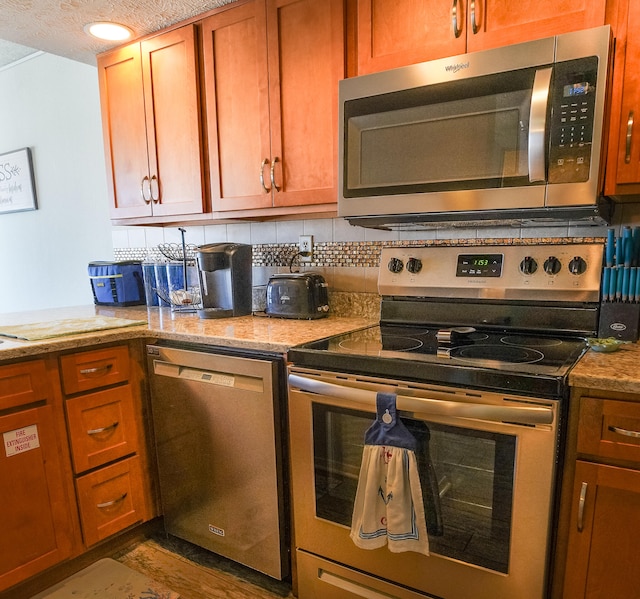 kitchen featuring stainless steel appliances, wood-type flooring, light stone counters, a textured ceiling, and tasteful backsplash