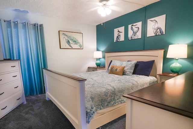 bedroom with a textured ceiling, dark colored carpet, and ceiling fan