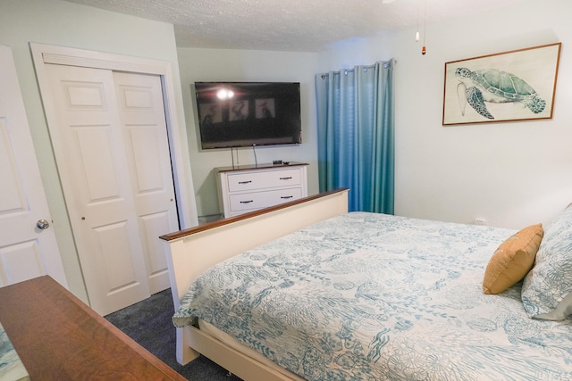 bedroom featuring a closet, a textured ceiling, and dark colored carpet