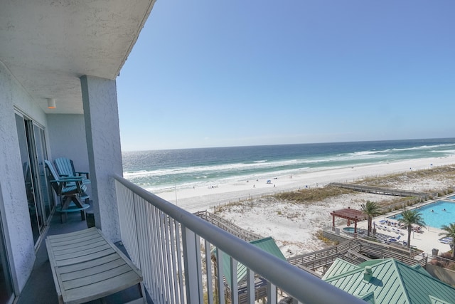 balcony featuring a water view and a beach view