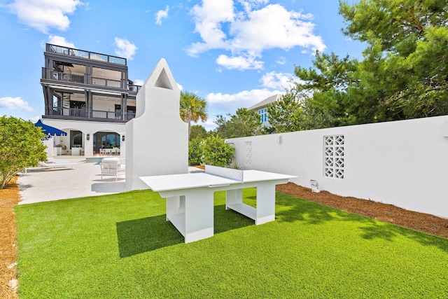 rear view of property featuring a patio, a balcony, and a yard