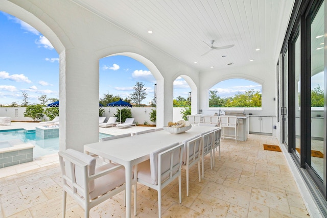 view of patio with exterior bar, ceiling fan, and a fenced in pool