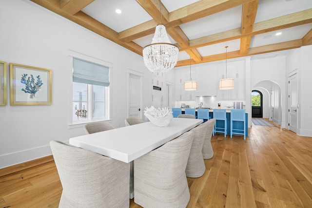 dining area with light hardwood / wood-style flooring, coffered ceiling, beam ceiling, and plenty of natural light