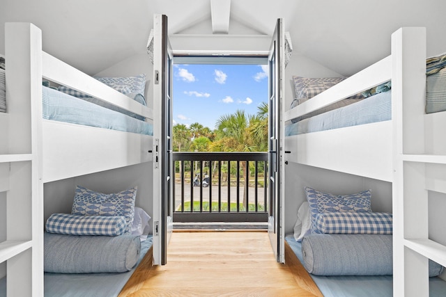 bedroom with lofted ceiling with beams and hardwood / wood-style flooring