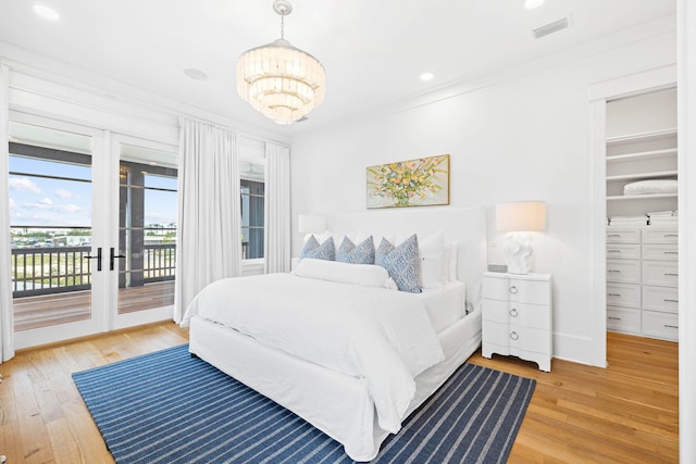 bedroom with ornamental molding, access to exterior, a spacious closet, light hardwood / wood-style flooring, and a closet