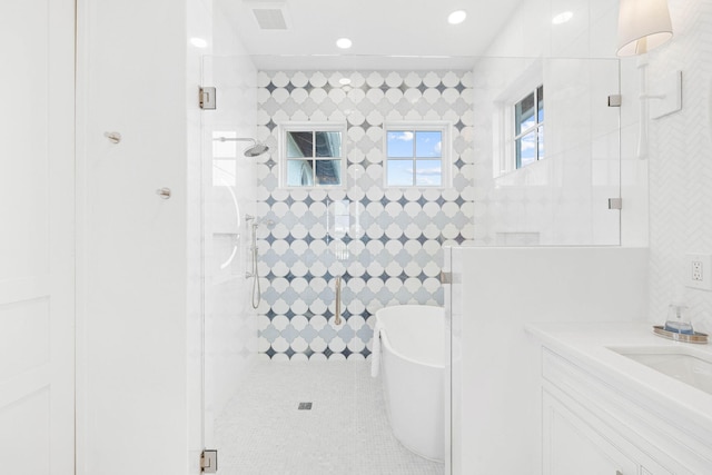 bathroom with tile walls, vanity, and separate shower and tub