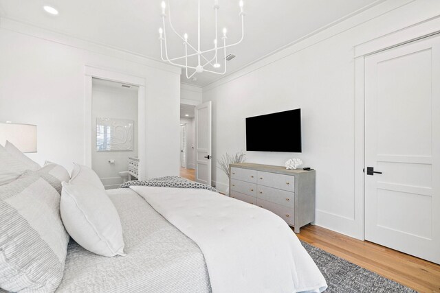 bedroom featuring hardwood / wood-style flooring, crown molding, and an inviting chandelier