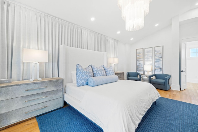 bedroom with hardwood / wood-style floors, lofted ceiling, and a chandelier