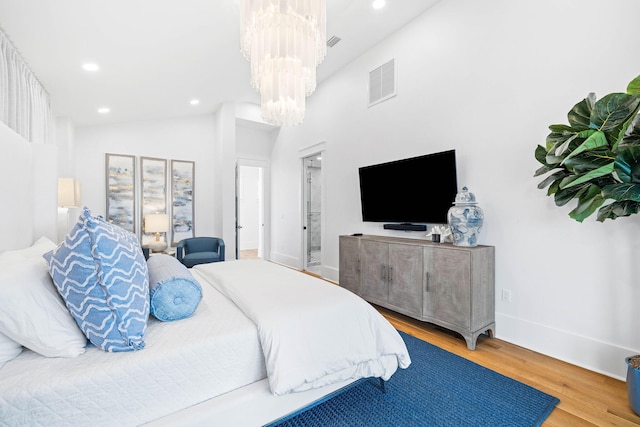 bedroom with hardwood / wood-style flooring, vaulted ceiling, and a notable chandelier