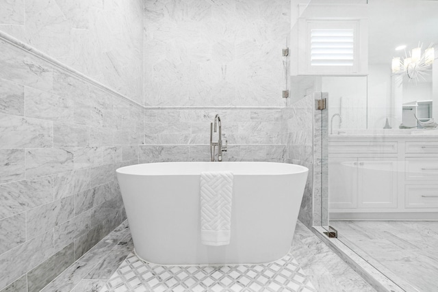 bathroom with a tub, vanity, and tile walls