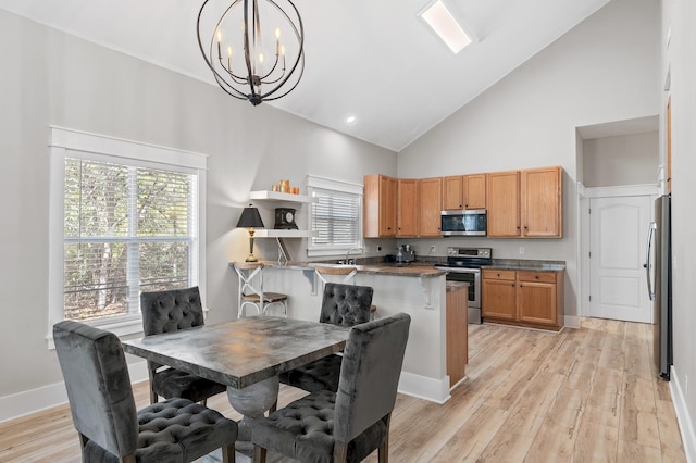 dining space featuring high vaulted ceiling, light wood-type flooring, and an inviting chandelier