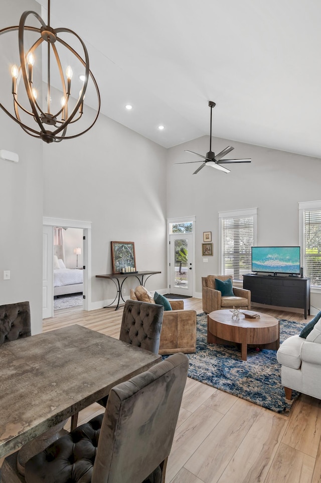 living room featuring high vaulted ceiling, light hardwood / wood-style flooring, and ceiling fan with notable chandelier