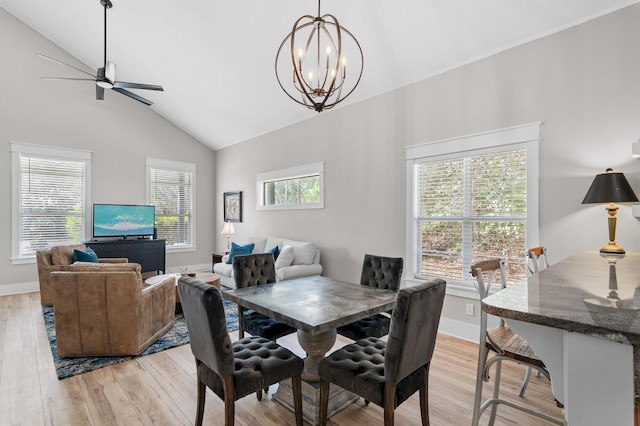 dining area with high vaulted ceiling, ceiling fan with notable chandelier, and light hardwood / wood-style flooring