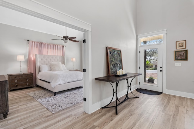 bedroom featuring access to exterior, a towering ceiling, light hardwood / wood-style flooring, and ceiling fan