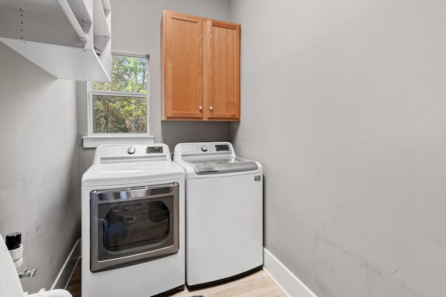 laundry room with light wood-type flooring, cabinets, and separate washer and dryer