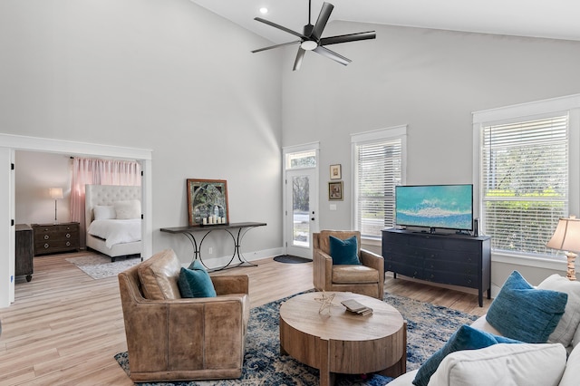 living room with high vaulted ceiling, ceiling fan, and light wood-type flooring