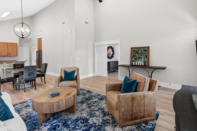 living room with high vaulted ceiling, light wood-type flooring, and an inviting chandelier