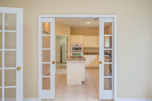 kitchen with french doors, white double oven, light tile patterned floors, and light stone counters