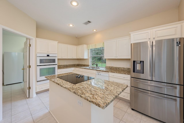 kitchen with a center island, light stone counters, white appliances, and white cabinetry