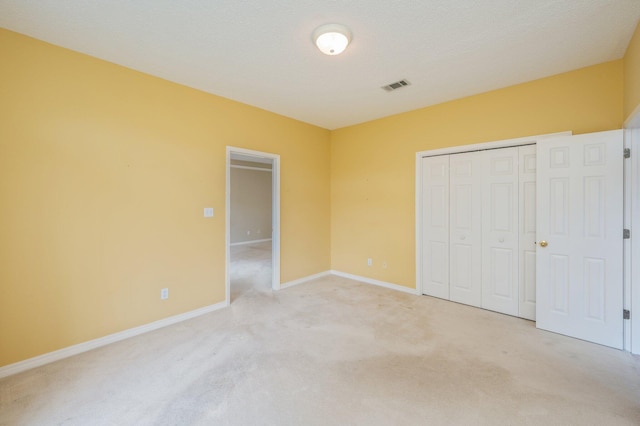 unfurnished bedroom featuring a textured ceiling, light carpet, and a closet