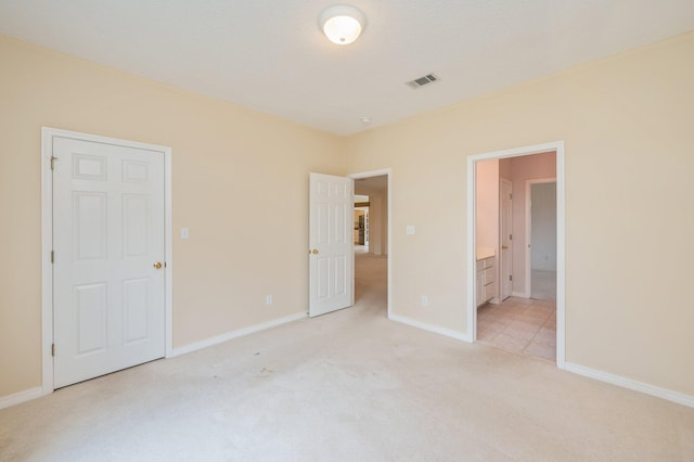 unfurnished bedroom with light colored carpet and ensuite bath