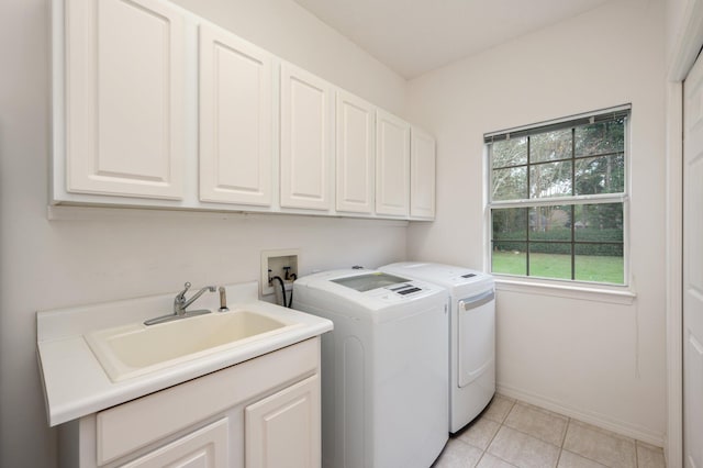 washroom with cabinets, light tile patterned floors, washing machine and clothes dryer, and sink