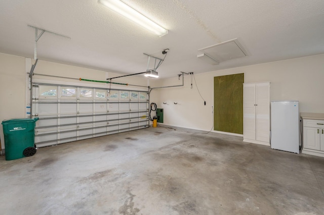 garage featuring white refrigerator and a garage door opener