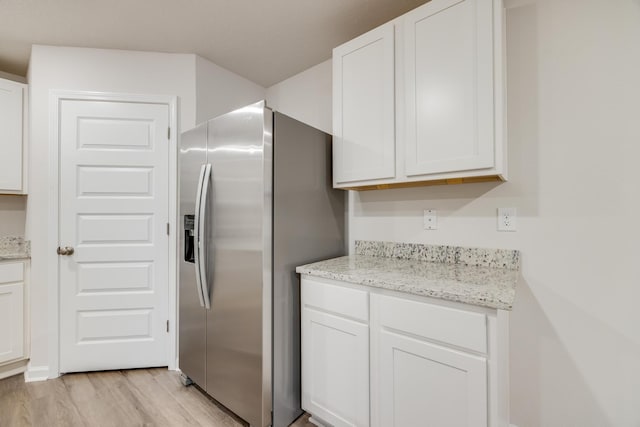 kitchen featuring white cabinets, stainless steel refrigerator with ice dispenser, light stone countertops, and light hardwood / wood-style flooring