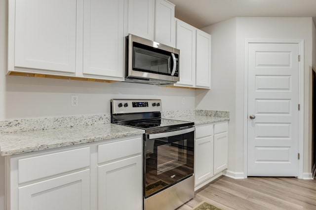 kitchen with white cabinetry, appliances with stainless steel finishes, light stone counters, and light hardwood / wood-style floors