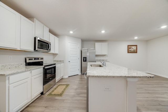 kitchen with white cabinetry, appliances with stainless steel finishes, sink, and a center island with sink