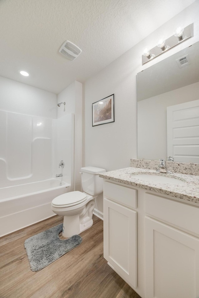 full bathroom featuring shower / tub combination, a textured ceiling, wood-type flooring, vanity, and toilet