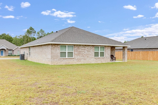 rear view of property featuring cooling unit and a yard