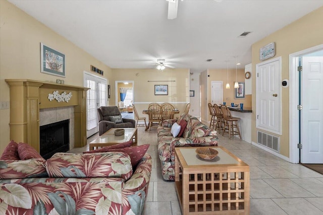 tiled living room featuring ceiling fan and a tiled fireplace