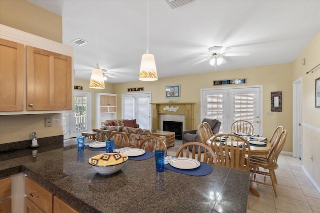 kitchen featuring ceiling fan, a tiled fireplace, plenty of natural light, and light tile patterned floors