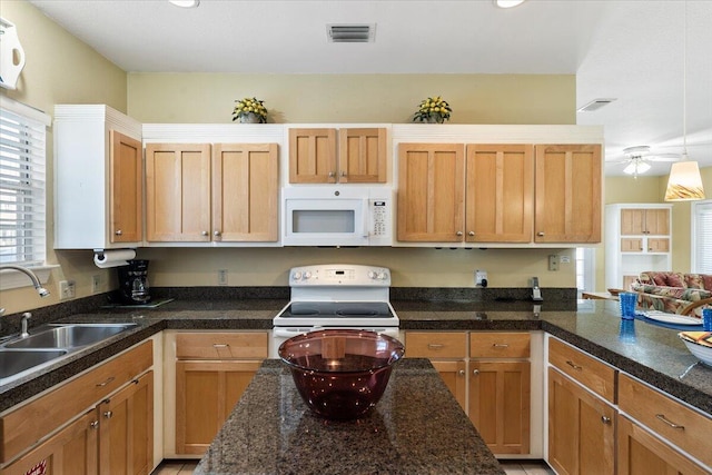 kitchen with dark stone counters, white appliances, ceiling fan, and sink