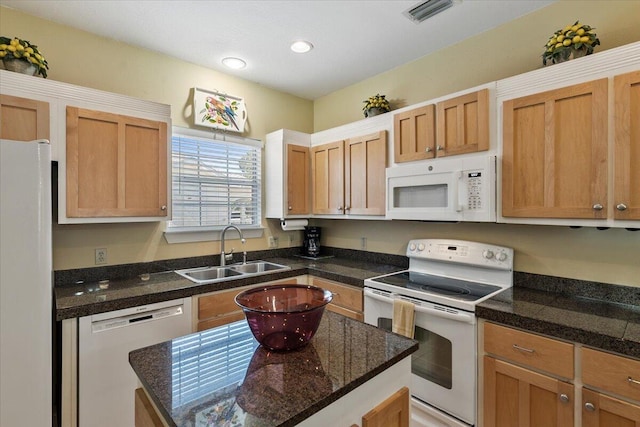 kitchen featuring white appliances, dark stone countertops, and sink