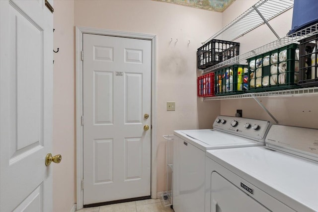 laundry area with washing machine and dryer and light tile patterned floors