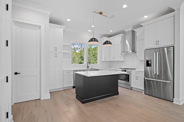 kitchen featuring a center island, wall chimney range hood, hanging light fixtures, high end appliances, and light hardwood / wood-style flooring