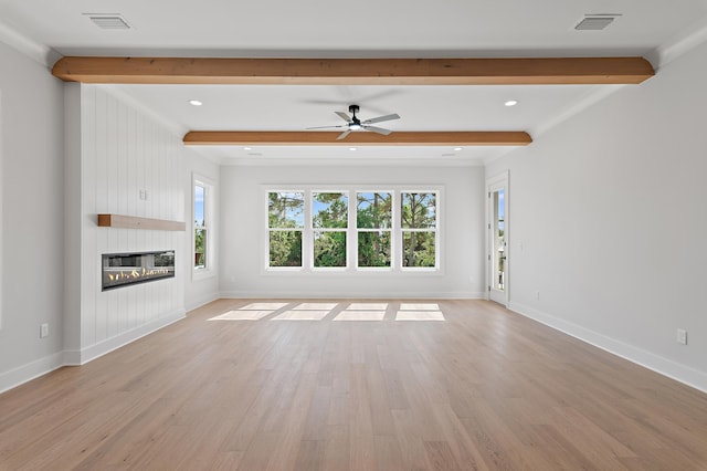 unfurnished living room with light hardwood / wood-style floors, beamed ceiling, and plenty of natural light