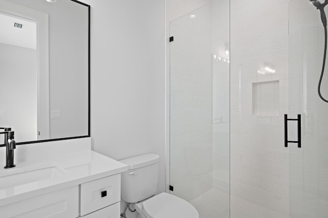 bathroom with vanity, toilet, and a shower with door