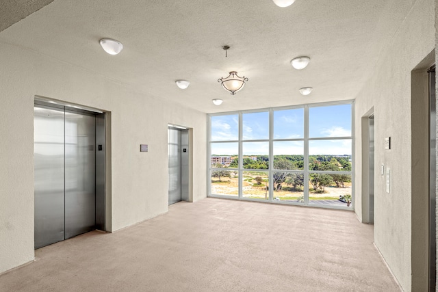 interior space with a textured ceiling, elevator, light carpet, and a closet